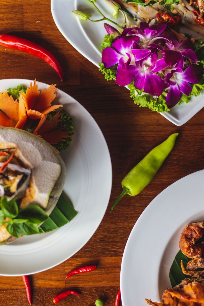 Delicious Thai dishes with fresh ingredients, vibrant presentation, and intricate garnishes on a wooden table.