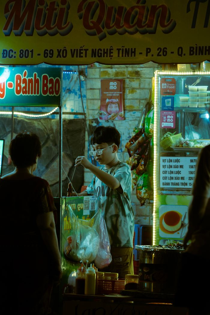 An illuminated street food stall in Vietnam at night, bustling with activity and authentic flavors.